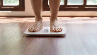 Fat diet and scale feet standing on electronic scales for weight control. Measurement instrument in kilogram for a diet control.