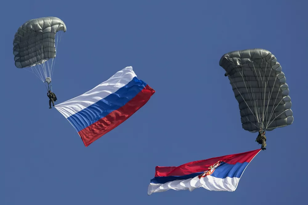 Serbian paratroopers descend to the ground holding Serbian and Russian (L) national flags during a training exercise in the village of Nikinci, west from Belgrade, November 14, 2014. Russian soldiers parachuted into open fields in western Serbia on Friday as part of an unprecedented joint military drill that has stirred controversy in the European Union candidate-country given the West-Russia standoff over Ukraine. The one-day anti-terrorist exercise, around 50 km (30 miles) from Serbia's border with NATO-member Croatia, illustrated the balancing-act Belgrade faces; safeguarding relations with its big-power ally while pursuing closer integration with Europe at a time of deep West-Russia tension. REUTERS/Marko Djurica (SERBIA - Tags: MILITARY POLITICS)