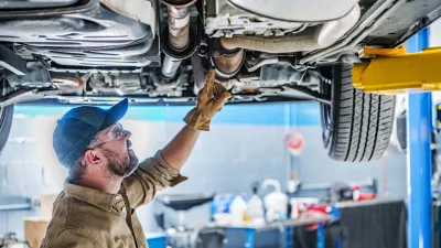 Professional Caucasian Mechanic Standing Under the Vehicle Lifted on Car Lift Checking the Condition of Catalytic Converter. Automotive Theme. / Foto: Istockphoto