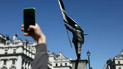 A person takes a picture of statue, depicting a figure carrying a flag covering their face and stepping off a plinth, by British street artist Banksy in London, Britain, May 1, 2026. REUTERS/Jack Taylor