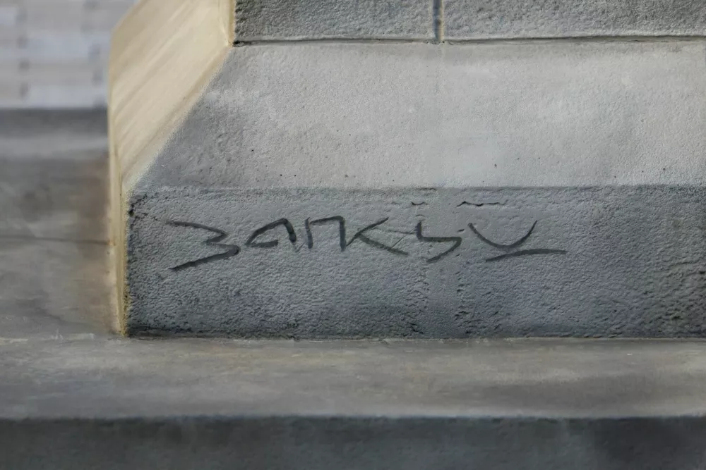 British street artist Banksy's signature on the base of a statue depicting a person stepping off the plinth with a flag covering their face, in London, Britain, April 30, 2026. REUTERS/Jack Taylor