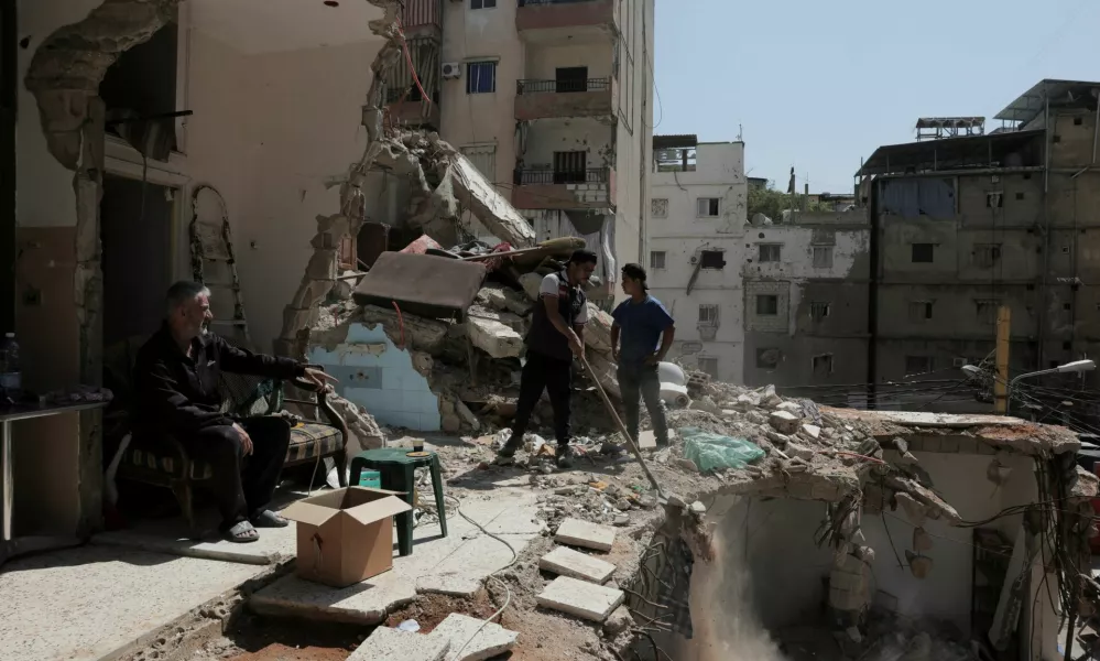 Ali Soueidan, 60, from southern Lebanon, looks at people cleaning his damaged house in the southern suburbs of Beirut, Lebanon, May 8, 2026. REUTERS/Raghed Waked