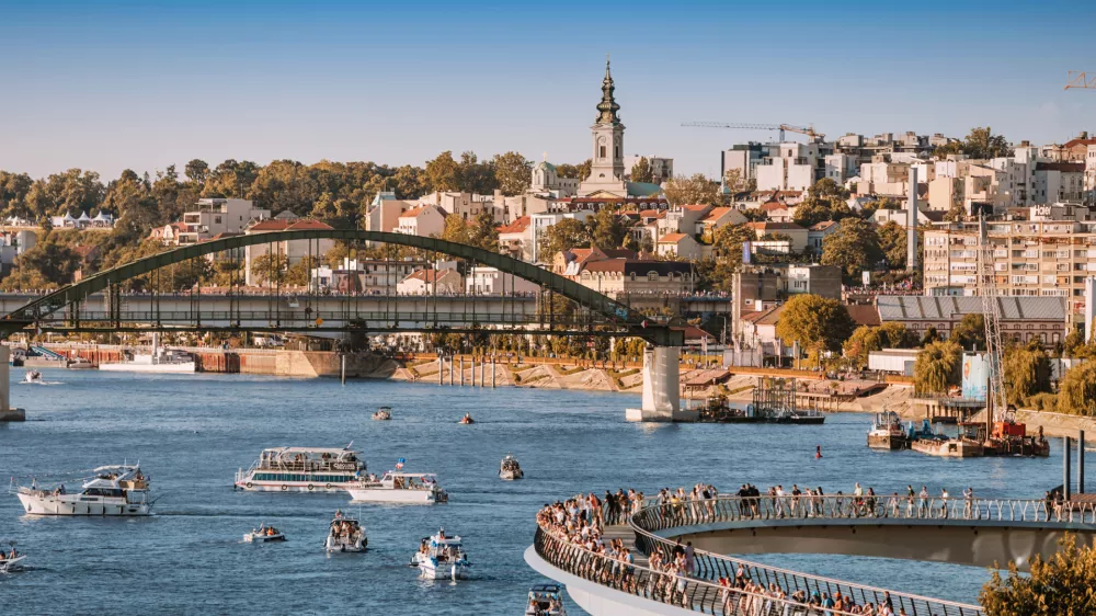 1 June 2025, Belgrade, Serbia: Modern pedestrian bridge over Sava River with tourists walking and enjoying the view