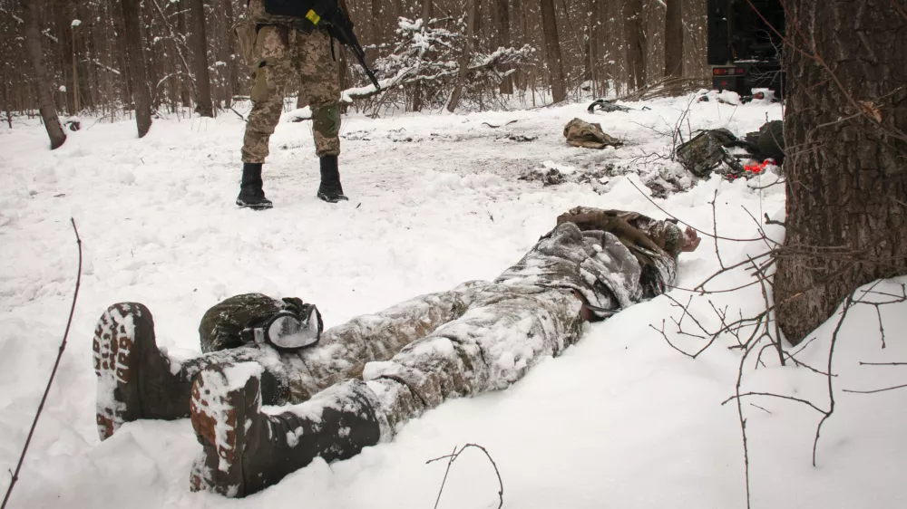 A volunteer of the Ukrainian Territorial Defense Forces looks at a dead body of a soldier lying in a forest in the outskirts of Kharkiv, Ukraine's second-largest city, Monday, March 7, 2022. Russia announced yet another cease-fire and a handful of humanitarian corridors to allow civilians to flee Ukraine. Previous such measures have fallen apart and Moscow&acirc;&euro;&trade;s armed forces continued to pummel some Ukrainian cities with rockets Monday. (AP Photo/Andrew Marienko).
