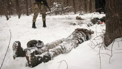 A volunteer of the Ukrainian Territorial Defense Forces looks at a dead body of a soldier lying in a forest in the outskirts of Kharkiv, Ukraine's second-largest city, Monday, March 7, 2022. Russia announced yet another cease-fire and a handful of humanitarian corridors to allow civilians to flee Ukraine. Previous such measures have fallen apart and Moscowâ€™s armed forces continued to pummel some Ukrainian cities with rockets Monday. (AP Photo/Andrew Marienko).