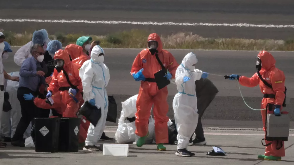 Passengers are sprayed with disinfectant by Spanish government officials before boarding a plane after disembarking from the hantavirus-stricken cruise ship MV Hondius at Tenerife airport in the Canary Islands, Spain, Sunday, May 10, 2026. (AP Photo/Arturo Rodriguez)
