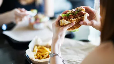 woman eating eating vegan meatless burger in restaurant during the day