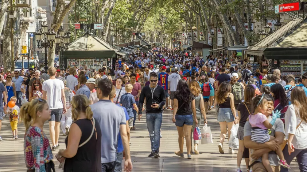 Barcelona, Spain - July 5, 2016: Hundreds of people promenading in the busiest street of Barcelona, the Ramblas. The street extends 1.2 kilometers connects the Placa de Catalunya in the centre with the Christopher Columbus Monument at Port Vell.