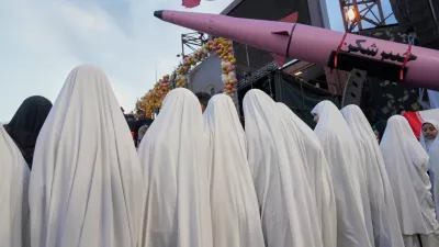 A group of girls stand beside a "Khaybar-buster" missile during a mass wedding ceremony for couples participating in the "Janfada" ("Sacrifice for Iran") pro-government campaign in Tehran, Iran, Monday, May 18, 2026. (AP Photo/Vahid Salemi)