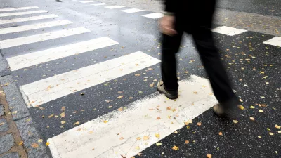 Man in black crossing street on wet autumn day