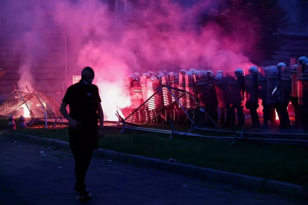 A demonstrator walks near riot police, as a flare emits smoke, during a student-led protest demanding snap parliamentary elections, as Serbia's anti-corruption movement enters a new phase, following the Novi Sad railway station canopy collapse that killed 16 people in 2024, in Belgrade, Serbia, May 23, 2026. REUTERS/Zorana Jevtic