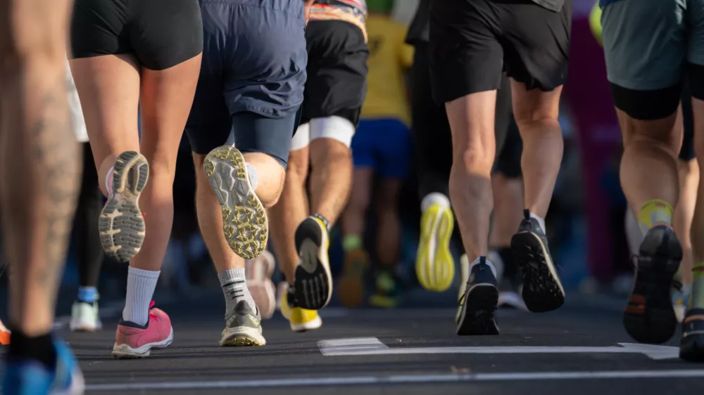 close up of diverse marathon runners feet in athletic shoes running on city pavement in Ljubljana urban marathon event on sunny day / Foto: Jairo Mesa