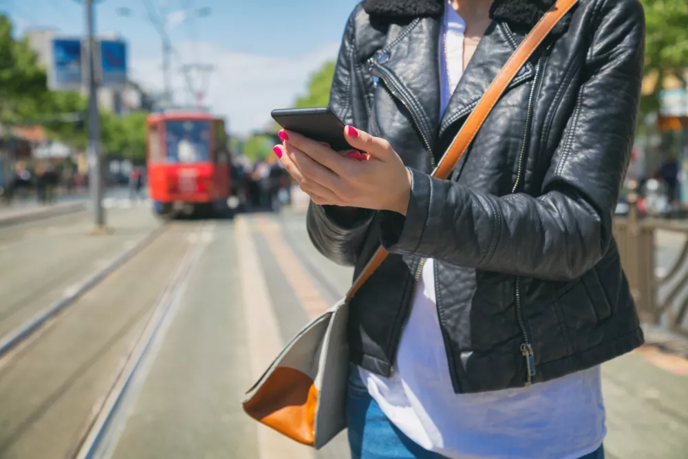 Using cellphone with defocused city tram. / Foto: M-gucci