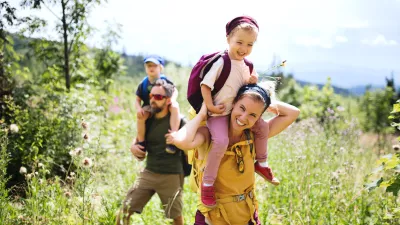Front view of family with small children hiking outdoors in summer nature. / Foto: Halfpoint Getty Images