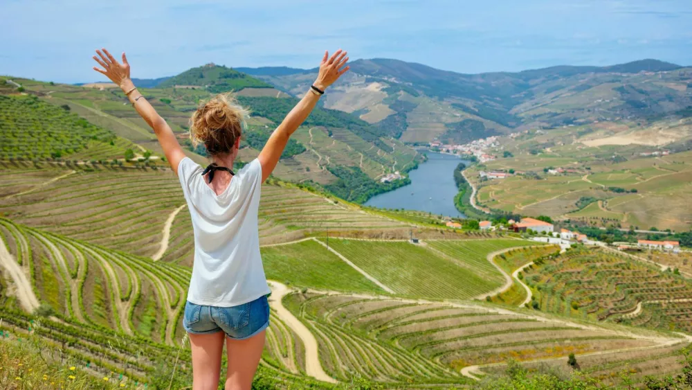 Happy traveler woman enjoying panoramic view of Douro valley in Portugal / Foto: Margouillatphotos