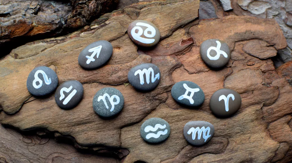 Zodiac symbols drawn on stones lie on a wooden table. Horoscope, fortune telling, predictions. / Foto: Oksana Lyskova Getty Images