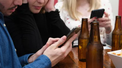 Unrecognizable three friends seeing something on their smartphone, drinking in a pub. Friendship concept. / Foto: Ladanifer Getty Images