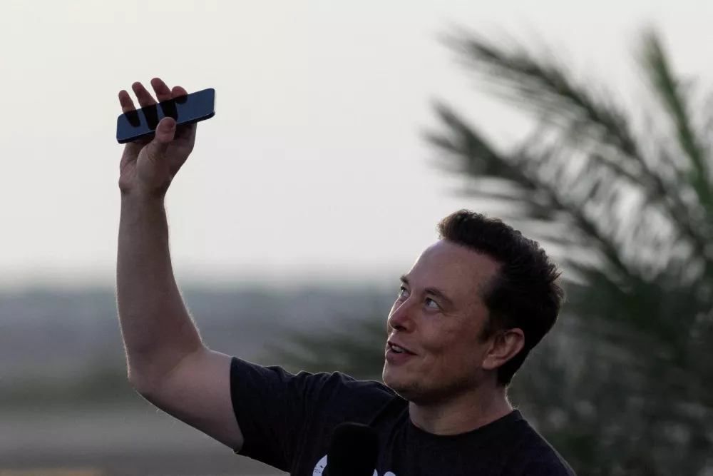 FILE PHOTO: Elon Musk raises his phone towards the sky during a joint news conference with T-Mobile CEO Mike Sievert (not pictured) at the SpaceX Starbase, in Brownsville, Texas, U.S., August 25, 2022. REUTERS/Adrees Latif/File Photo