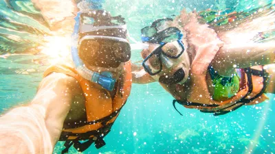 Senior happy couple taking selfie in tropical sea excursion with water camera - Boat trip snorkeling in exotic scenarios - Active retired elderly and fun concept on scuba diving - Warm vivid filter / Foto: Viewapart