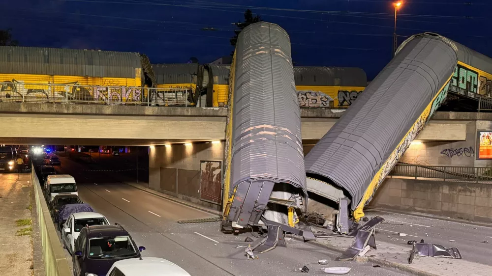 Two cars of a freight train which derailed after a collision, fell off a bridge and lay on a road in Munich, Germany, June 20, 2026.  REUTERS/Christine Uyanik