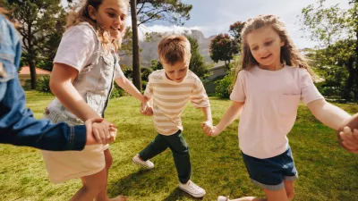 A group of happy children holding hands and playing on a sunny day in a park, enjoying outdoor activities and showcasing friendship, joy, and togetherness in a vibrant and lively environment.