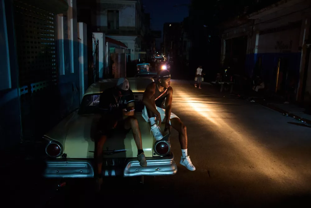 Men sit on the trunk of a car during a blackout in Havana, Cuba, Tuesday, July 14, 2026. (AP Photo/Ramon Espinosa)
