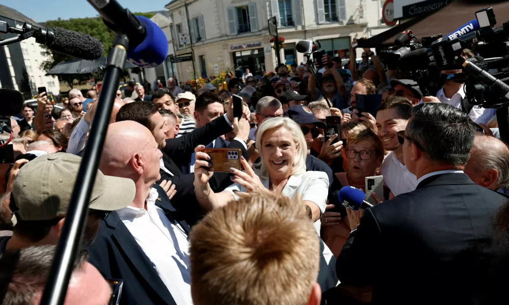 FILE PHOTO: French far-right leader Marine Le Pen and Jordan Bardella, president of the French far-right Rassemblement National (National Rally - RN) political party, make selfies with supporters surrounded by journalists in La Fleche, in the Sarthe department, France, July 8, 2026. REUTERS/Benoit Tessier/File Photo