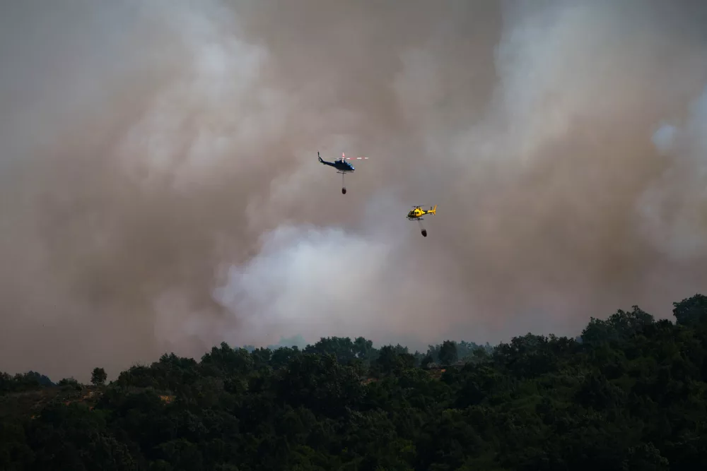 Firefighting helicopters drop water on the flames as a wildfire advances near Burgohondo, &Aacute;vila province, Spain, Friday, July 24, 2026. (AP Photo/Manu Fernandez)