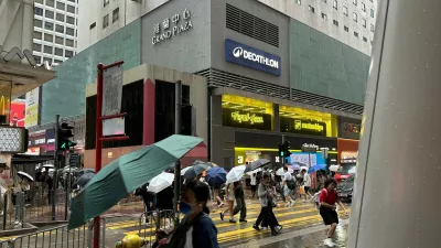 Passersby walk in Hong Kong's Mong Kok district under heavy rain and wind ahead of Typhoon Noul on Saturday, July 25, 2026. (AP Photo/Chan Ho-him)