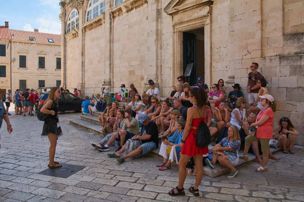Dubrovnik. Croatia - November 01, 2025: Visitors gather on the stone steps of the famous baroque stairway in Stari Grad on a sunny day.