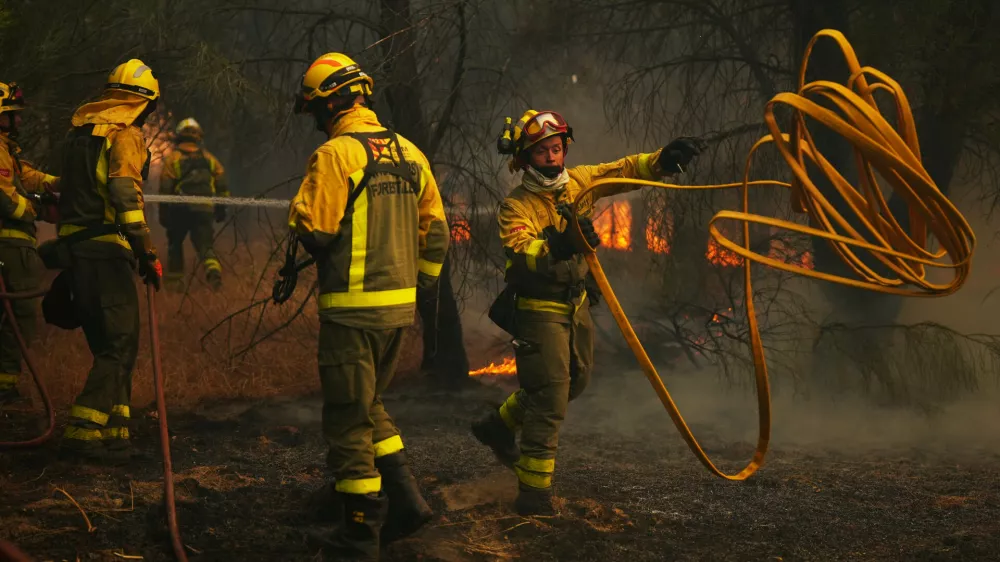 Firefighters battle a wildfire in San Martin de Valdeiglesias, west of Madrid, Spain, Sunday, July 26, 2026. (AP Photo/Manu Fernandez)