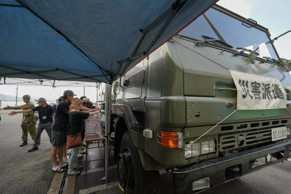 Residents receive a water supply after water service was disrupted following an earthquake in Hikawa, Kumamoto Prefecture, southern Japan, Thursday, July 30, 2026. (AP Photo/Hiro Komae)