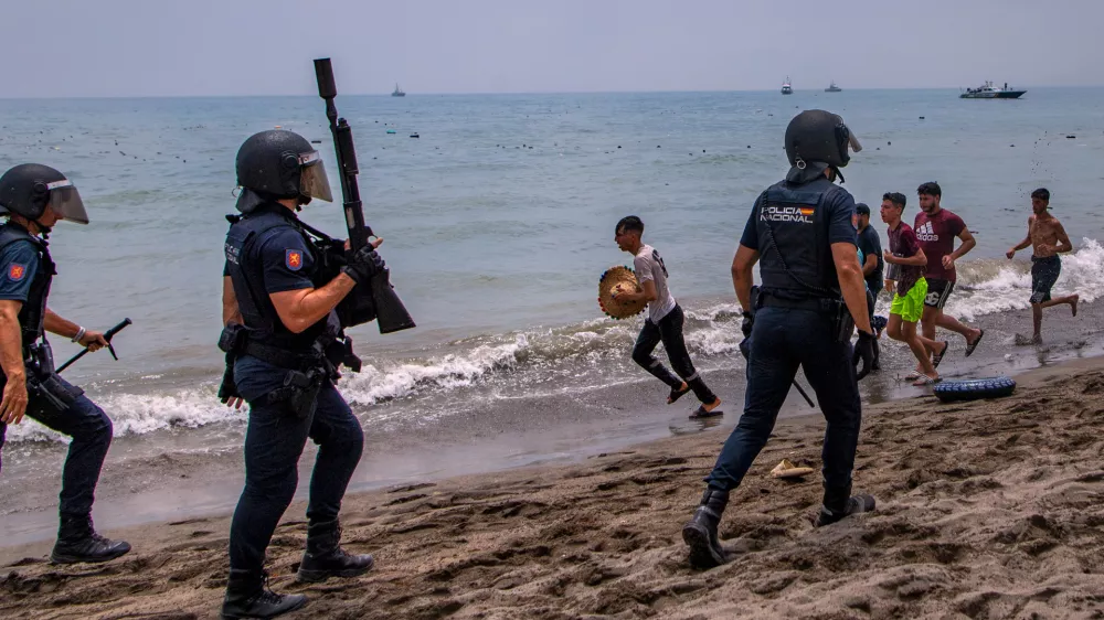 Spanish police officers respond as migrants cross from Morocco into the Spanish enclave of Ceuta, Thursday, July 30, 2026. (AP Photo/Antonio Sempere)