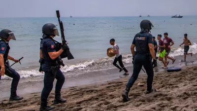 Spanish police officers respond as migrants cross from Morocco into the Spanish enclave of Ceuta, Thursday, July 30, 2026. (AP Photo/Antonio Sempere)