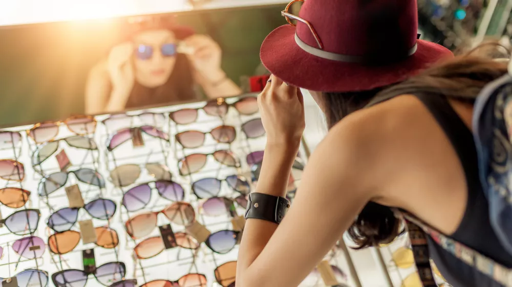 Happy woman buying sunglasses in shop on the street / Foto: Guruxoox Getty Images