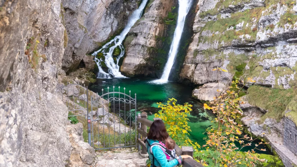 Alpine waterfall Savica in the nation park Triglav, Slovenia. Mother carrying baby in front. / Foto: Blazekg Getty Images