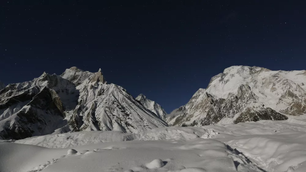 The world's second largest mountain, the 8,611 meter high K2 (seen in the distance), and the 8,051 meter high Broad Peak (R), are illuminated by the moon at Concordia, the confluence of the Baltoro and Godwin-Austen glaciers, in the Karakoram mountain range in Pakistan September 7, 2014. While other parts of Pakistan and northern India were flooded, Concordia in the Karakoram mountain range was covered with a seasonally unusual amount of snow. Geographically, Pakistan is a climbers paradise. It rivals Nepal for the number of peaks over 7,000 meters and is home to the world's second tallest mountain, K2, as well as four of the world's 14 summits higher than 8,000 meters. In more peaceful times, northern Pakistan's unspoilt beauty was a major tourist draw but the potentially lucrative industry has been blighted by years of violence. The number of expeditions has dwindled, wrecking communities dependant on climbing for income and starving Pakistan's suffering economy of much-needed dollars. Picture taken September 7, 2014. REUTERS/Wolfgang Rattay (PAKISTAN - Tags: SOCIETY ENVIRONMENT TRAVEL TPX IMAGES OF THE DAY) ATTENTION EDITORS - PICTURE 32 OF 32 FOR WIDER IMAGE STORY 'K2 - THE SAVAGE MOUNTAIN' SEARCH 'RATTAY K2' FOR ALL IMAGES
