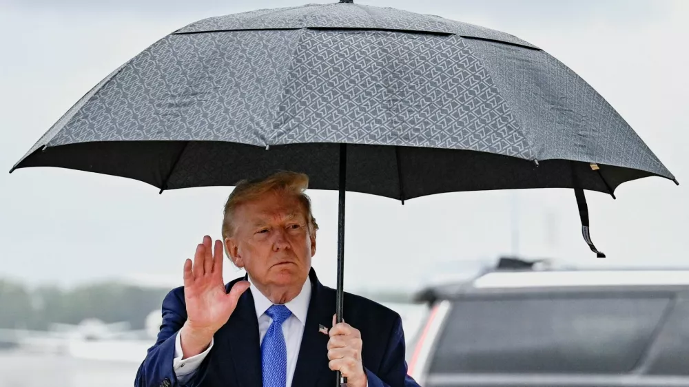 U.S. President Donald Trump gestures as he holds an umbrella after disembarking Air Force One at Joint Base Andrews, in Maryland, U.S., August 2, 2026. REUTERS/Daniel Heuer
