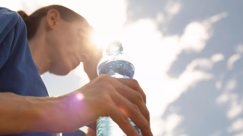 Woman drinking water in extreme summer heat wave.