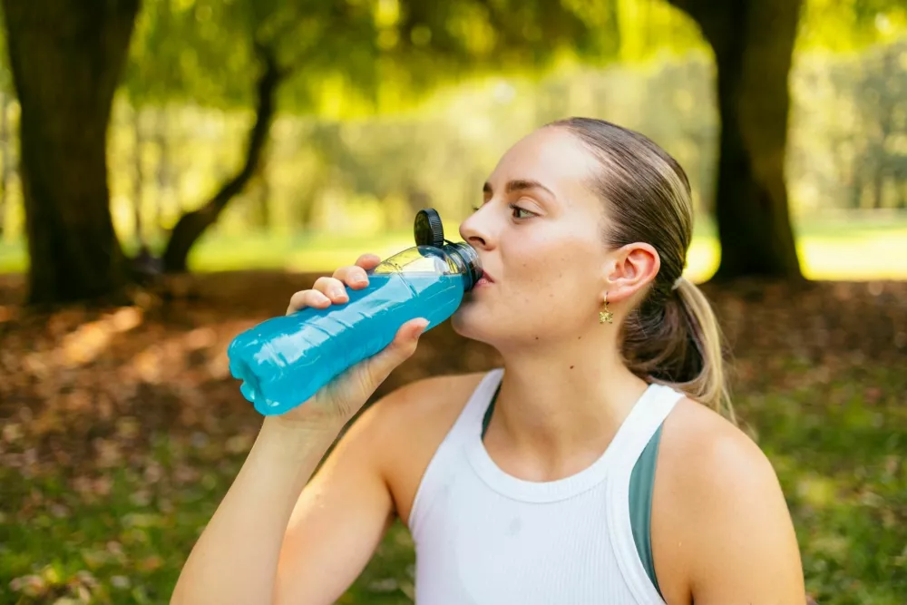 Young woman hydrating with sports drink after workout / Foto: Alberto Van Herckenrode