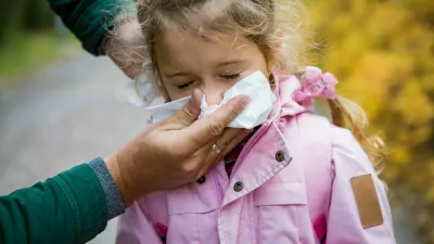 Father wiping daughter's nose with handkerchief. Sick little girl with cold and flu standing outdoors. Preschooler sneezing, coughing, having runny red nose. Autumn street background / Foto: Suzi Media Production