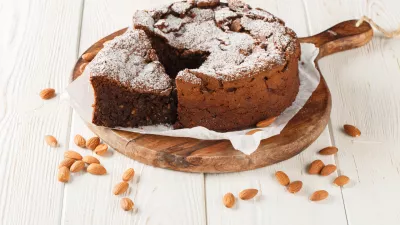 Italian Torta Caprese is a decadent, flourless cake made with dark chocolate and almonds closeup on the wooden board on the table. Horizontal / Foto: Alleko
