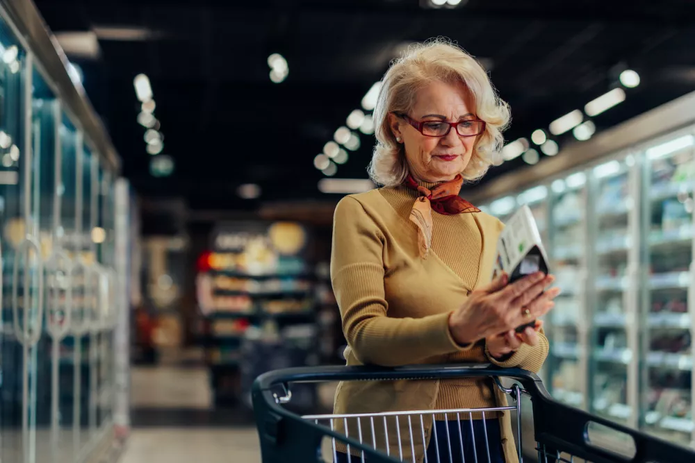 Beautiful mature woman choosing a cereal from shelf shopping for groceries at the supermarket and reading label / Foto: Bernardbodo Getty Images