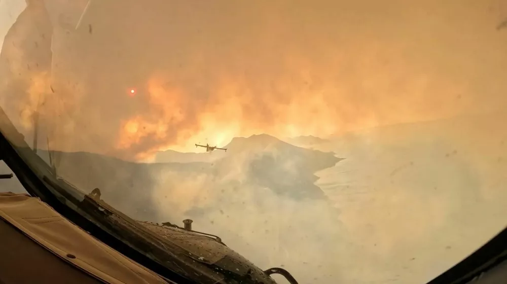 Smoke rises from a wildfire as a firefighting aircraft overflies the area, as seen from the window of another plane, in a location given as the Dalmatia region, Croatia, in this screengrab from video released on August 14, 2026. Croatian Ministry of Defence/Handout via REUTERS THIS IMAGE HAS BEEN SUPPLIED BY A THIRD PARTY / Foto: Croatian Ministry Of Defence