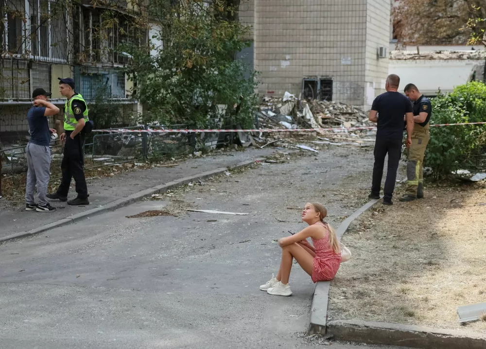 A girl sits near an apartment building damaged during yesterday's missile strike, amid Russia's attack on Ukraine, in Kyiv, Ukraine, August 21, 2026. REUTERS/Gleb Garanich