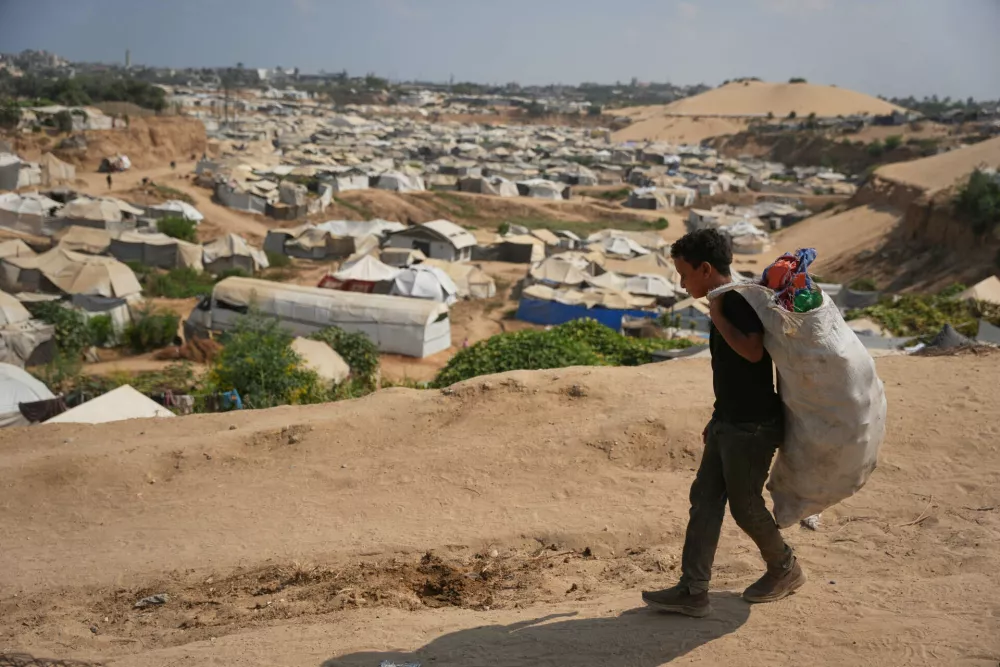 A Palestinian boy leaves a garbage dump after collecting combustible materials to use as fuel for cooking due to a shortage of cooking gas, in Deir al-Balah, central Gaza Strip, Saturday, Aug. 22, 2026. (AP Photo/Abdel Kareem Hana)