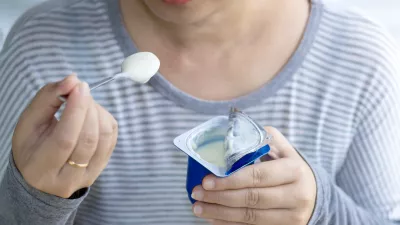 Beautiful woman eating yogurt in the morning, her hand holding a cup of yogurt and a spoon. Yogurt made from milk fermented by added bacteria, often sweetened and flavored. selective focus. / Foto: Pong-photo9 Getty Images