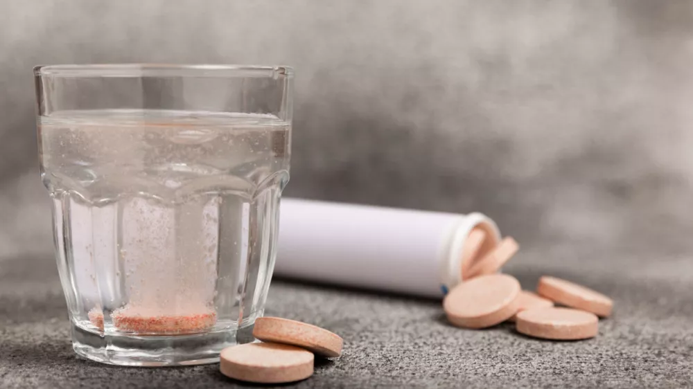 Effervescent tablet in a glass of water on a textured background. Vitamins. Health concept. Immunity drug. Space for copy. Space for text.