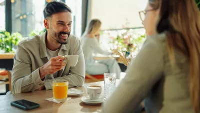 Happy couple sipping coffee and engaging in lively conversation at a cafe, cherishing their time together and enjoying each other's company / Foto: Zamrznutitonovi