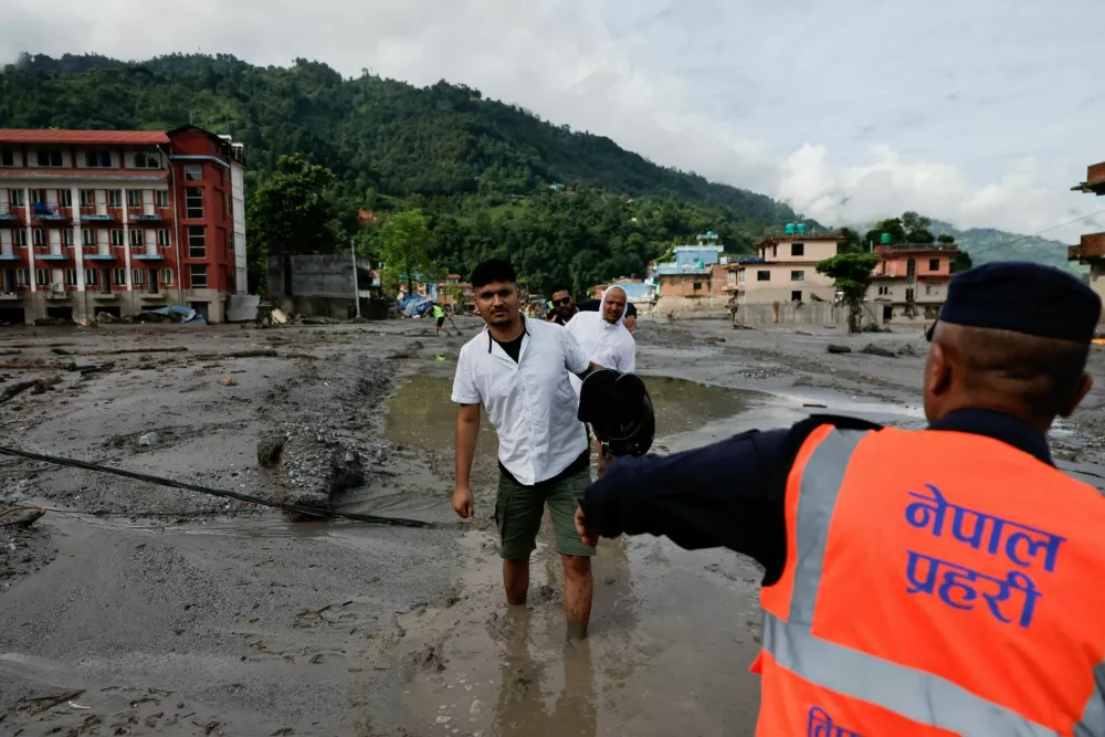 People wade through muddy waters following devastating floods, in Trishuli in Nuwakot district, Nepal, August 27, 2026. REUTERS/Navesh Chitrakar